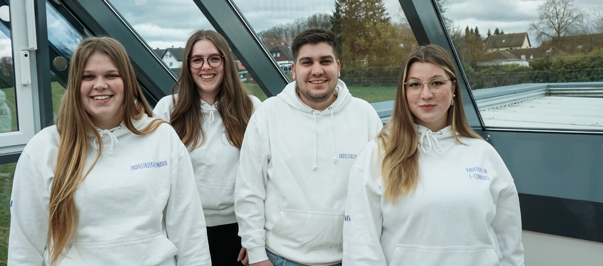 Vier Auszubildende der Firma Rolf Fensterbau mit weißen Pullis 